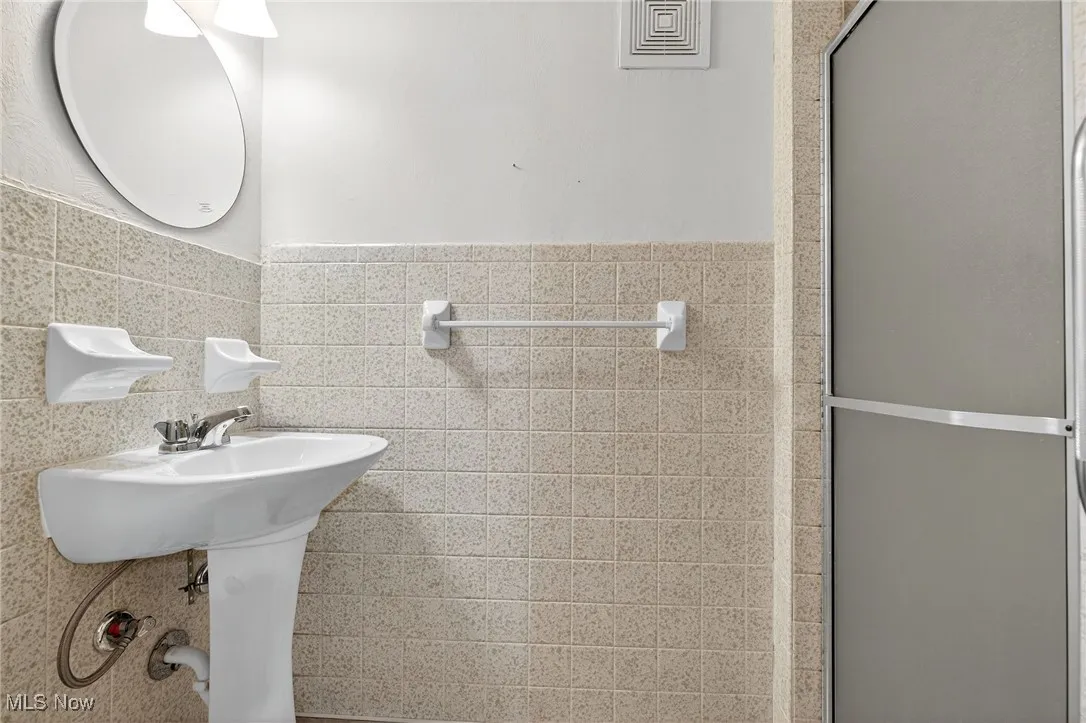 Full bath featuring tile walls, a shower stall, and a wainscoted wall