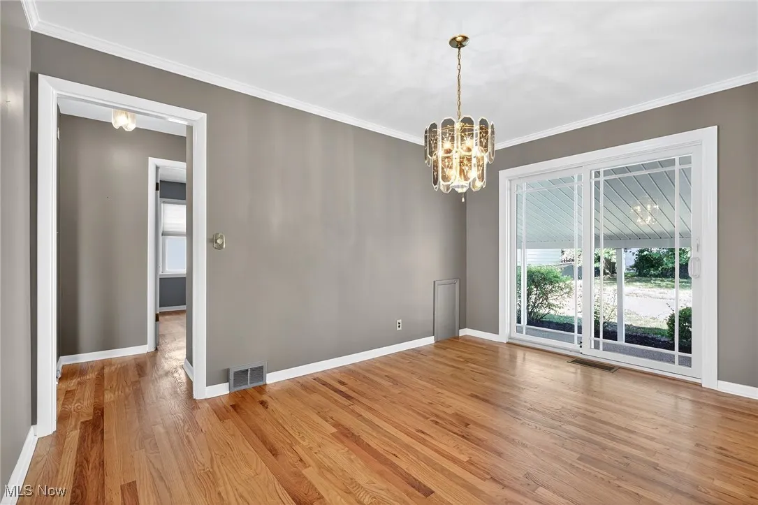 Unfurnished dining area featuring a chandelier, light wood-style floors, and ornamental molding