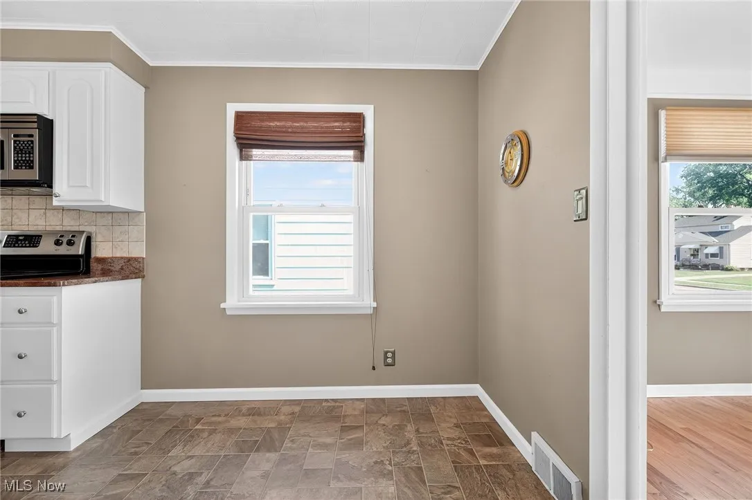 Unfurnished dining area with ornamental molding, stone finish flooring, and healthy amount of natural light