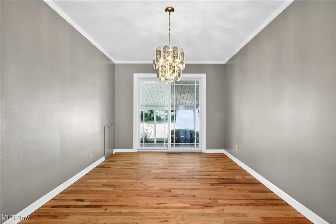 Unfurnished dining area with ornamental molding, a chandelier, and light wood-type flooring