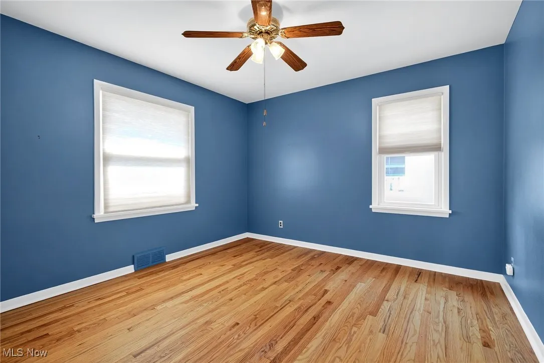 Spare room with wood finished floors and ceiling fan