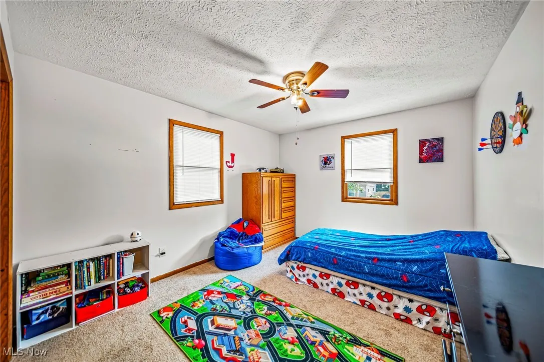 Carpeted bedroom with a textured ceiling and ceiling fan