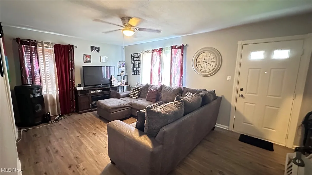 Living room with light wood finished floors, plenty of natural light, and ceiling fan