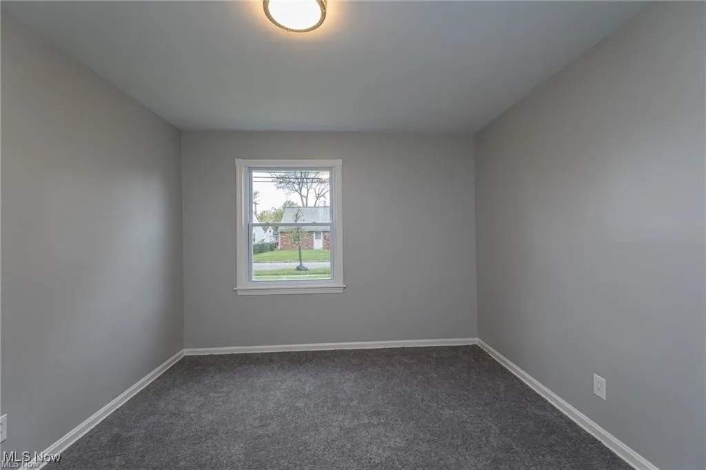 Spare room with dark carpet and baseboards