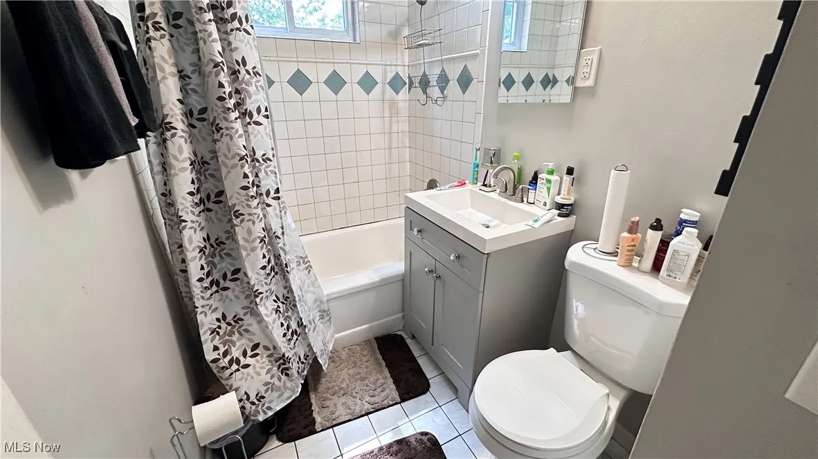Bathroom with vanity, shower / bath combination with curtain, and tile patterned flooring