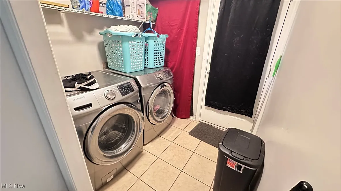 Laundry room with light tile patterned floors and washer and clothes dryer