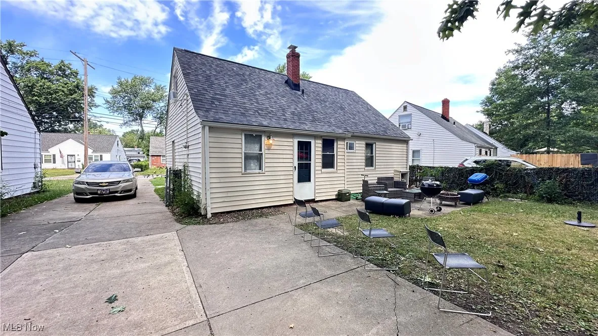 Rear view of house featuring roof with shingles, a chimney, and a patio area