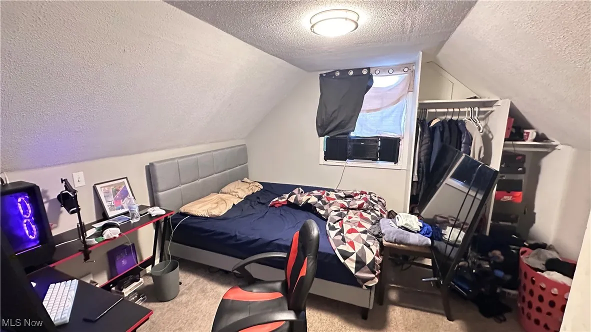 Carpeted bedroom featuring a textured ceiling and lofted ceiling