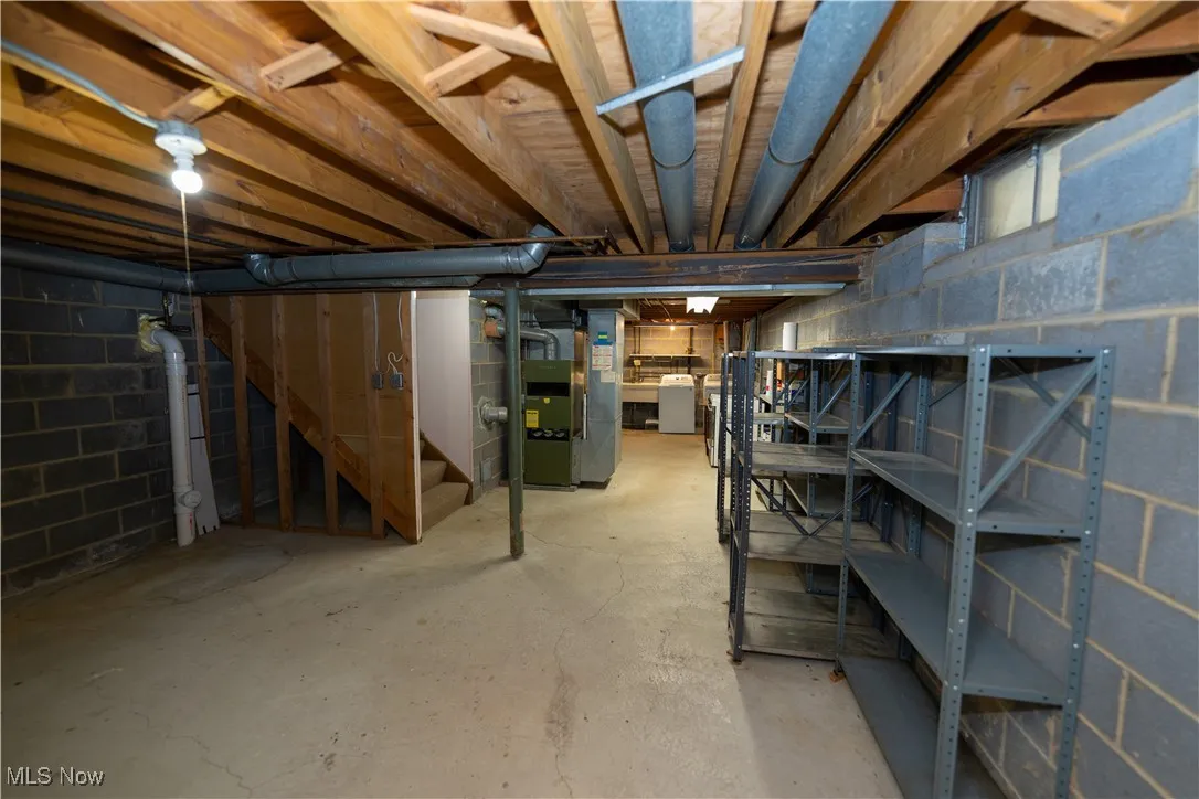 Unfinished below grade area with stairway, heating unit, and washer / dryer