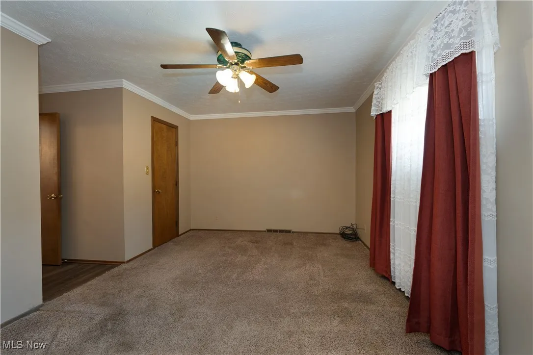 Master bedroom with ornamental molding, a ceiling fan, and updated carpet