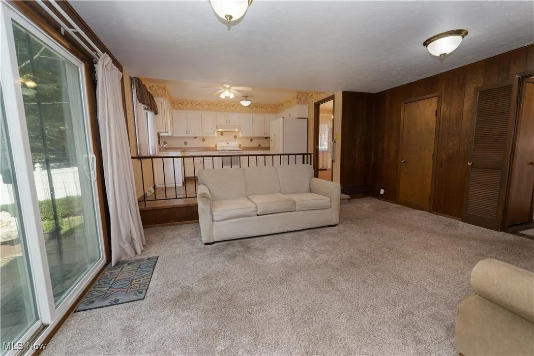 Family room with updated carpet and sliding glass doors leading to concrete back patio