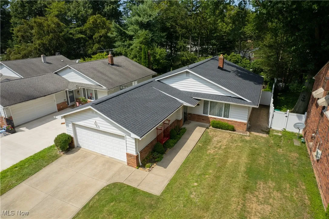 Aerial front view of property and surrounding area with a tree filled landscape