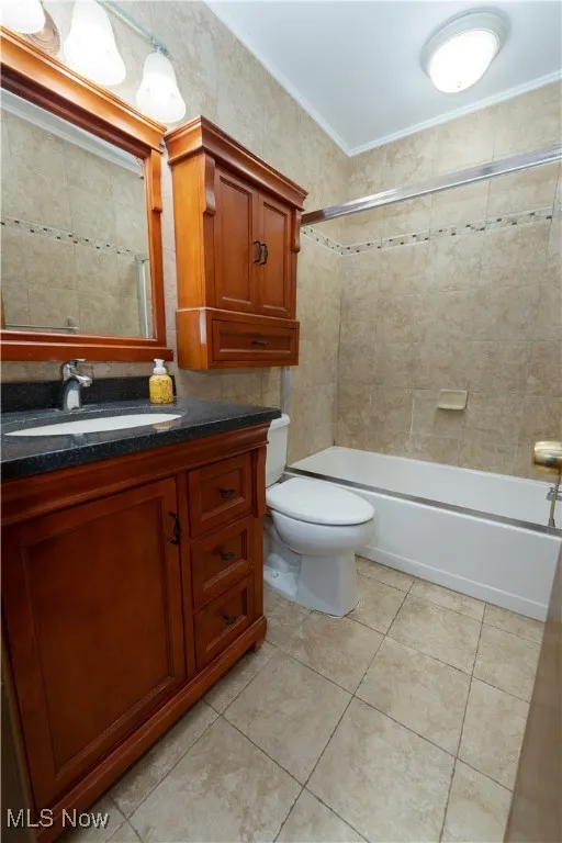 Full bath featuring vanity with granite countertop,  shower combination, tile patterned flooring, and ornamental molding