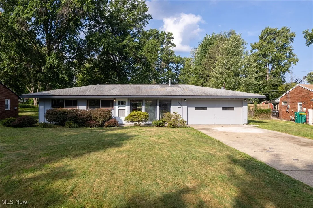 Ranch-style house with a front yard and concrete driveway