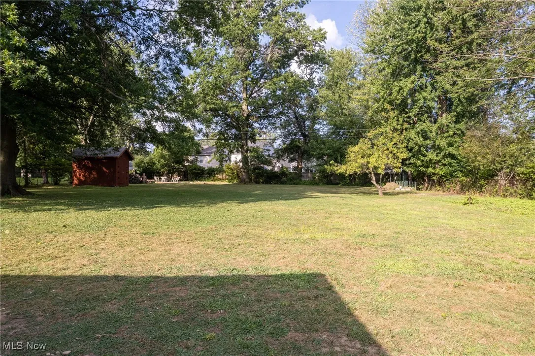 View of fenced backyard, shed, new firepit.