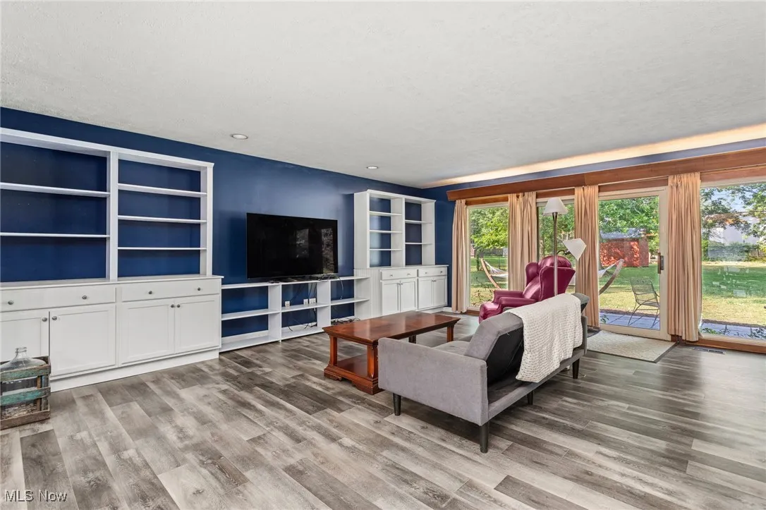Living room with recessed lighting, laminate flooring, built in shelving and patio doors leading to new patio & fenced backyard.