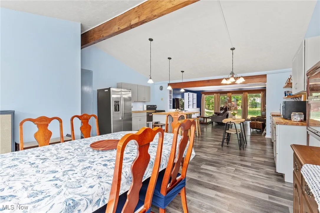 Eat in Kitchen featuring laminate floors, beam ceiling, and high vaulted ceiling.