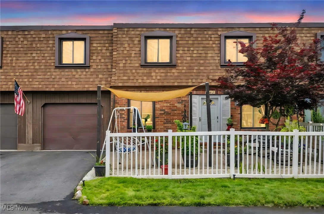 View of front of property featuring mansard roof, a fenced front yard, brick siding, driveway, and a garage