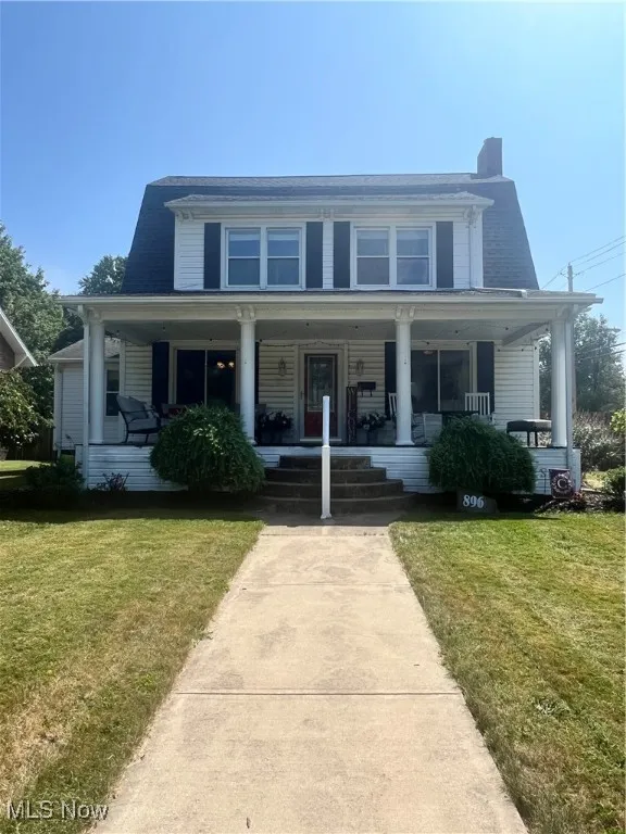 View of front of house featuring a front lawn, covered porch, and a chimney