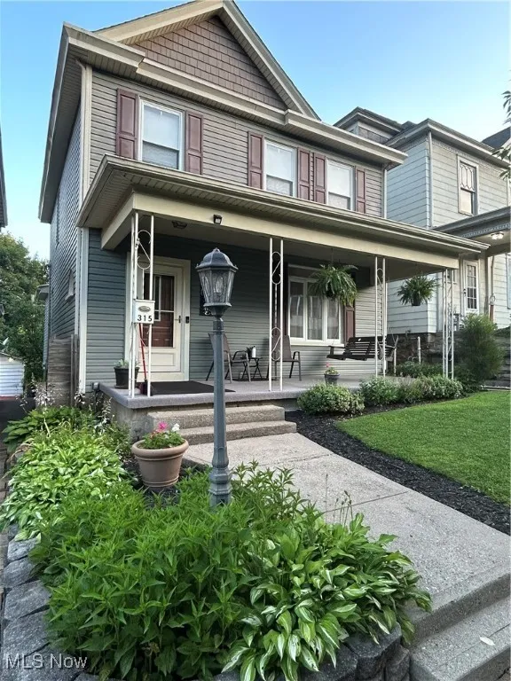 View of front of property with covered porch and a front lawn