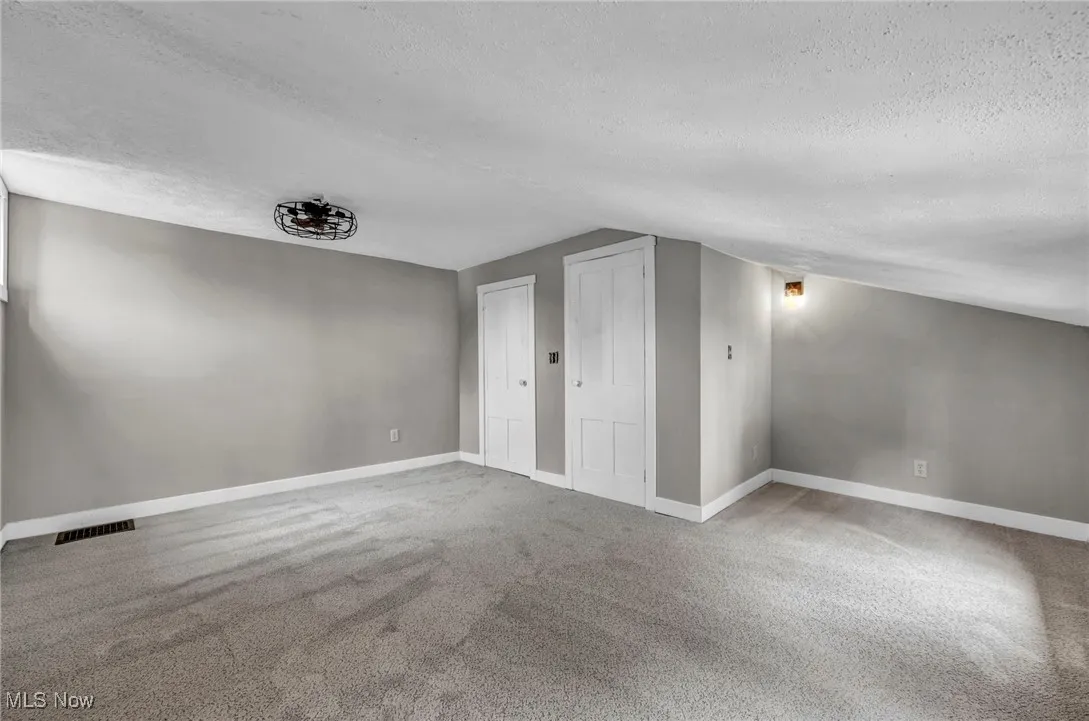 Additional living space with a textured ceiling and carpet floors