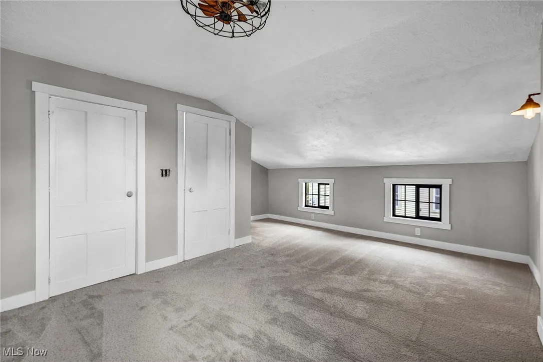 Bonus room featuring lofted ceiling, carpet flooring, and a textured ceiling