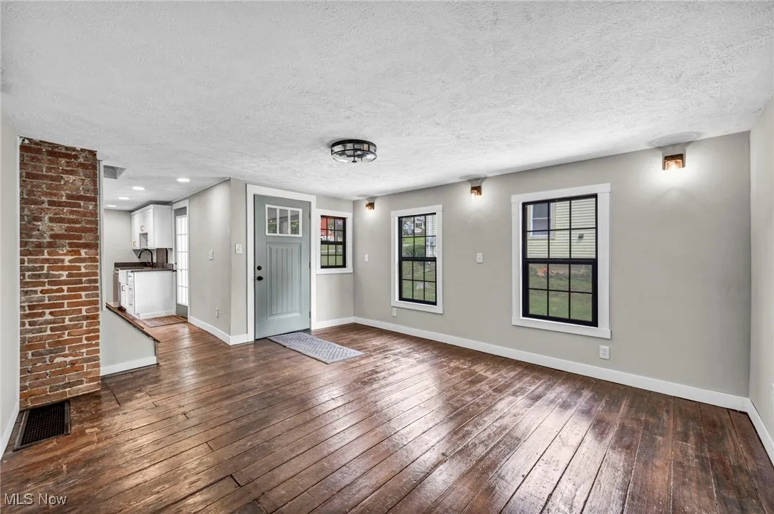 Unfurnished living room featuring dark wood-style flooring and a textured ceiling