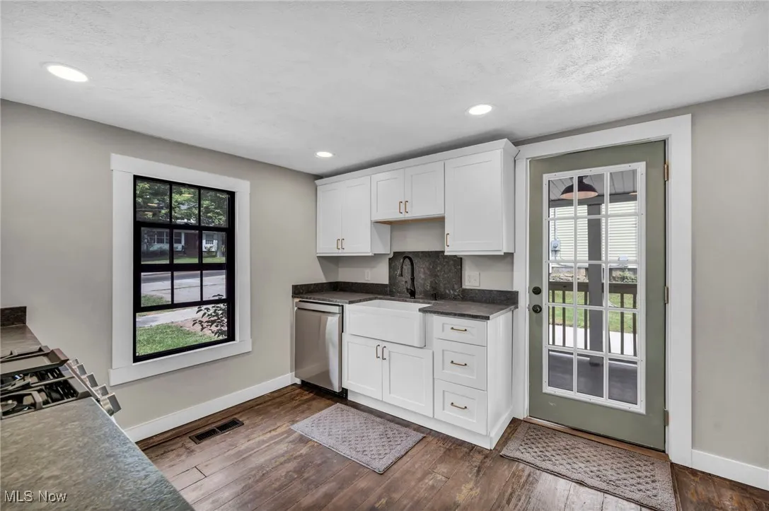 Kitchen with dark countertops, dark wood-style floors, stainless steel appliances, white cabinets, and recessed lighting