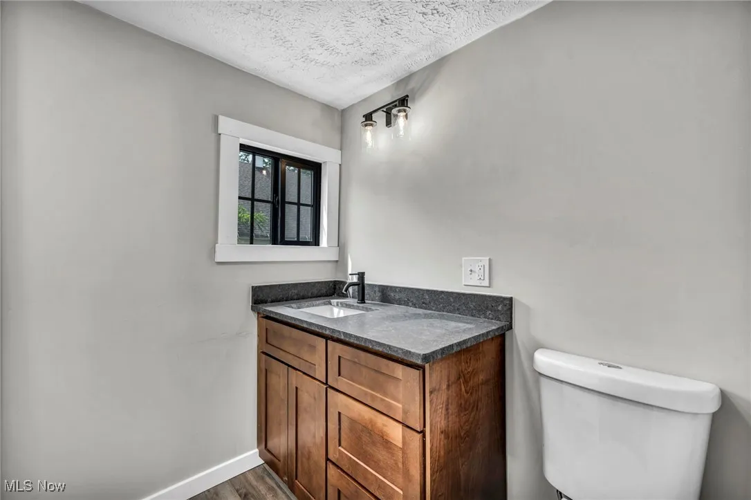 Bathroom with a textured ceiling, vanity, and wood finished floors