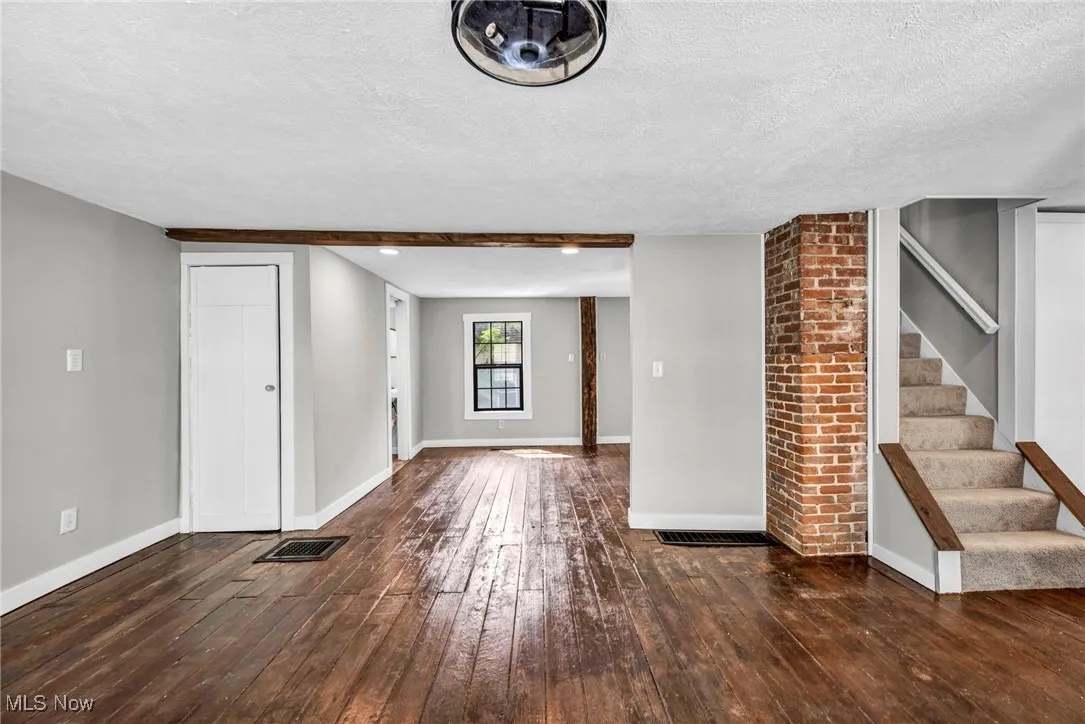 Unfurnished living room with hardwood / wood-style flooring, a textured ceiling, and stairway