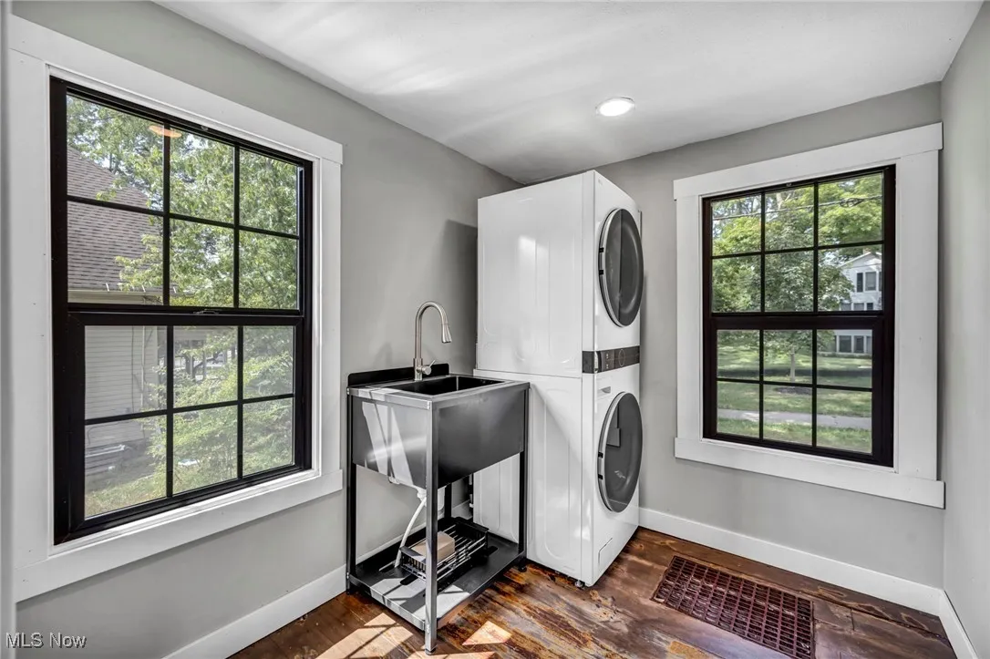 Laundry room featuring stacked washer / dryer, dark wood-style flooring, and recessed lighting
