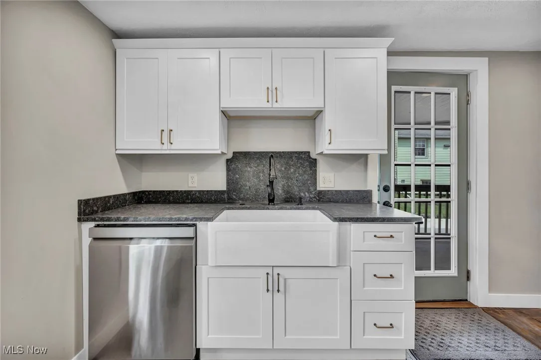 Kitchen featuring stainless steel dishwasher, white cabinets, and wood finished floors