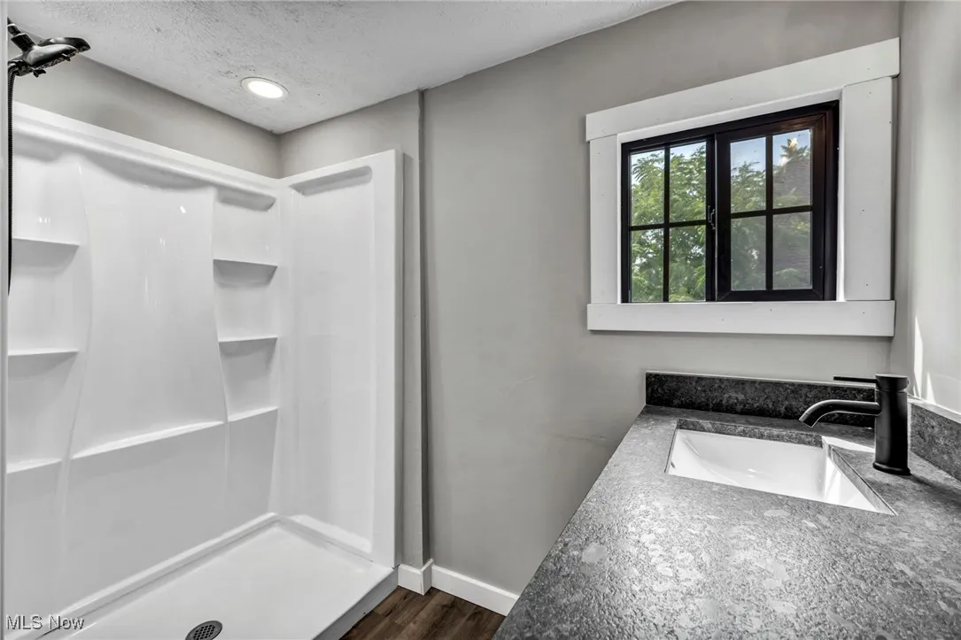 Bathroom featuring a stall shower, a textured ceiling, wood finished floors, recessed lighting, and vanity