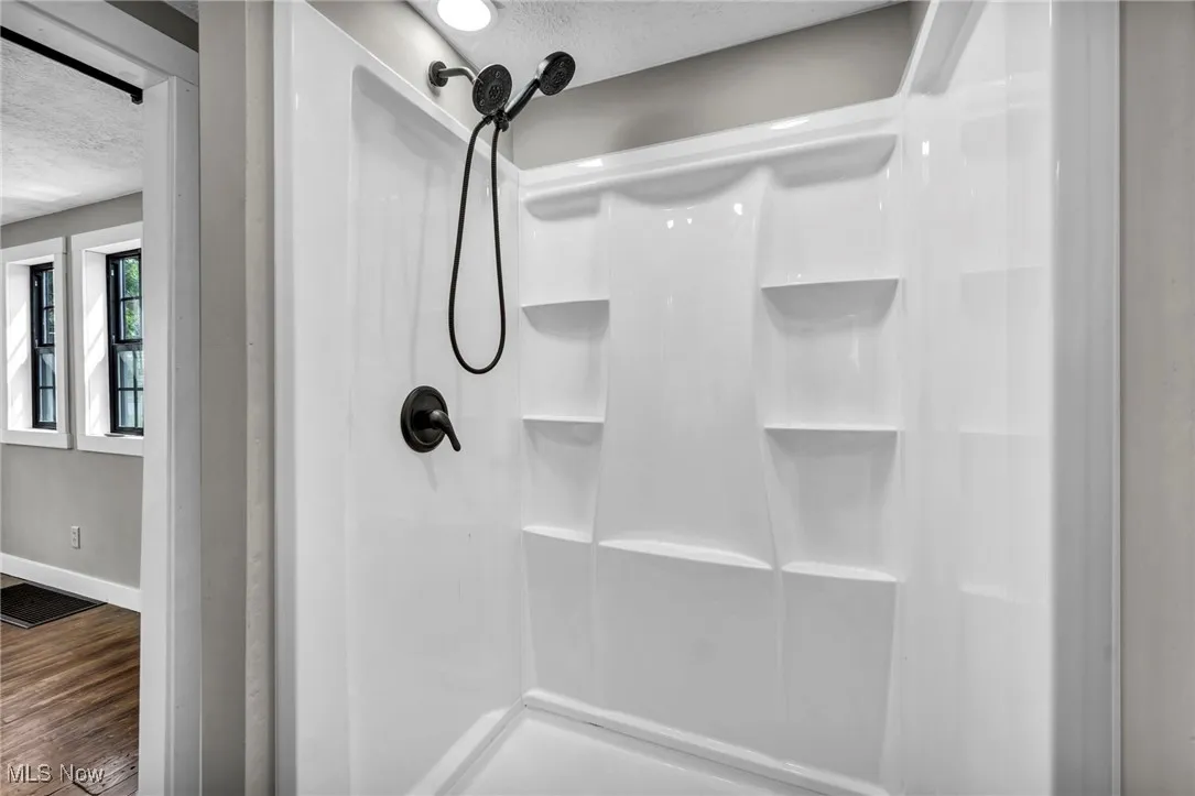 Full bathroom with a textured ceiling, a shower, and wood finished floors