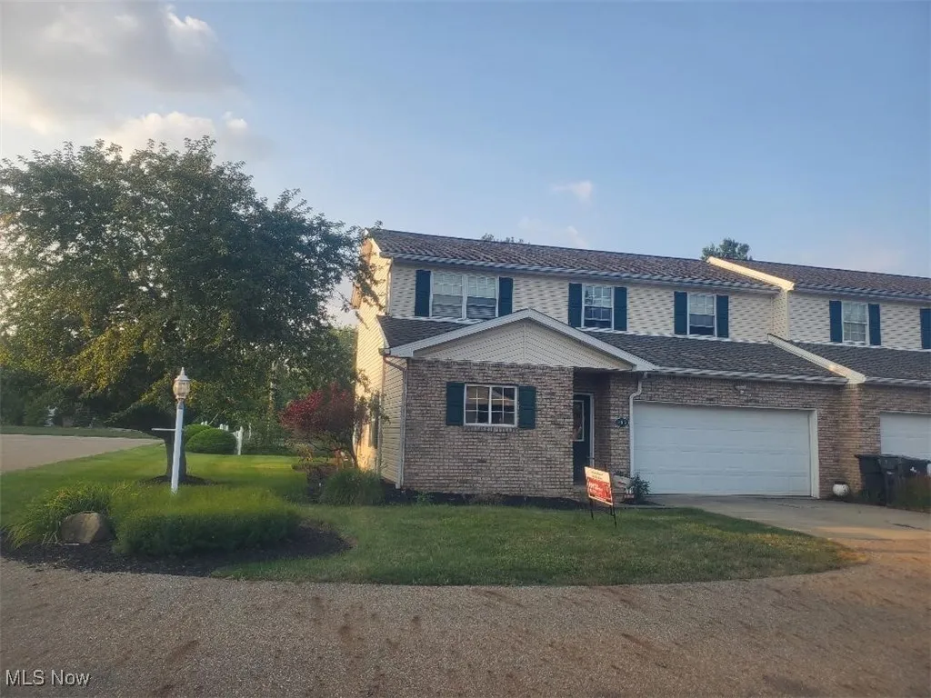 Traditional home with concrete driveway, brick siding, and a front lawn