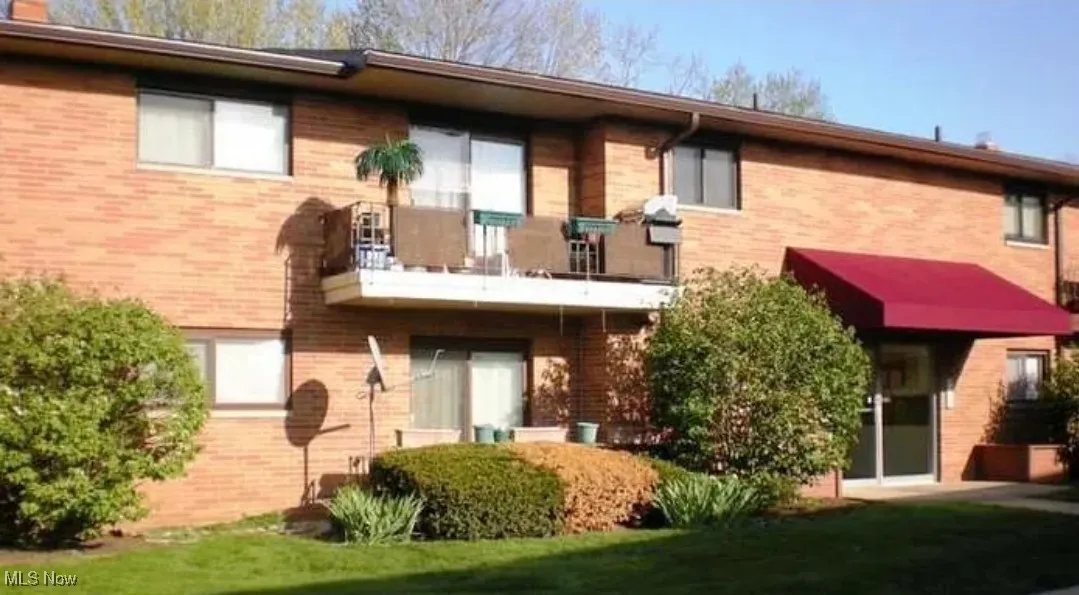 Back of house with brick siding and a balcony