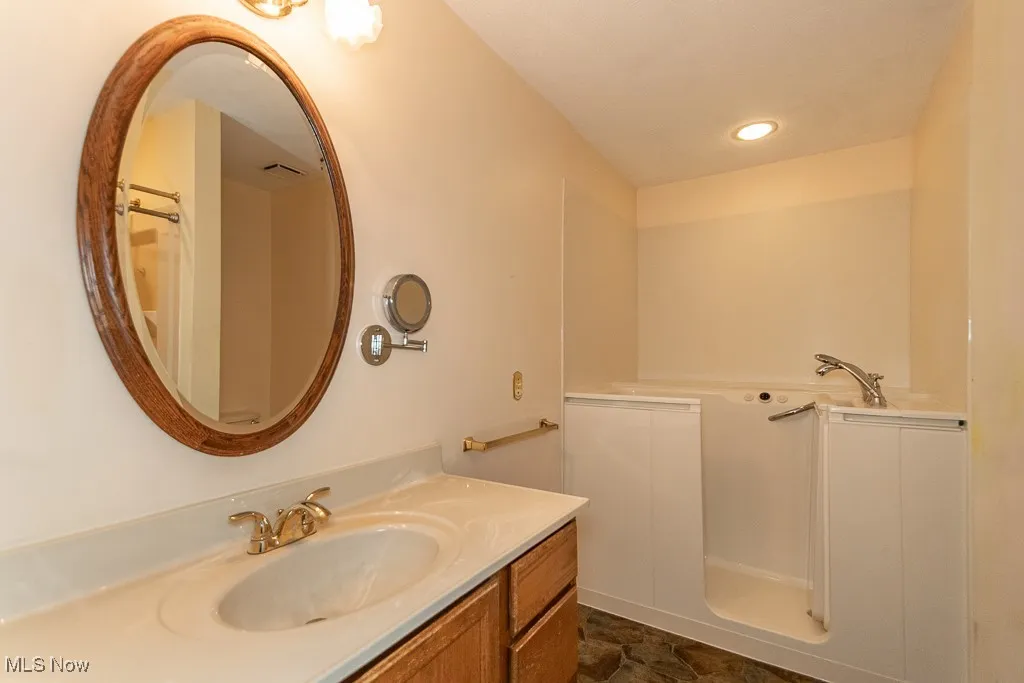 Full bath featuring vanity, a tub, and a shower