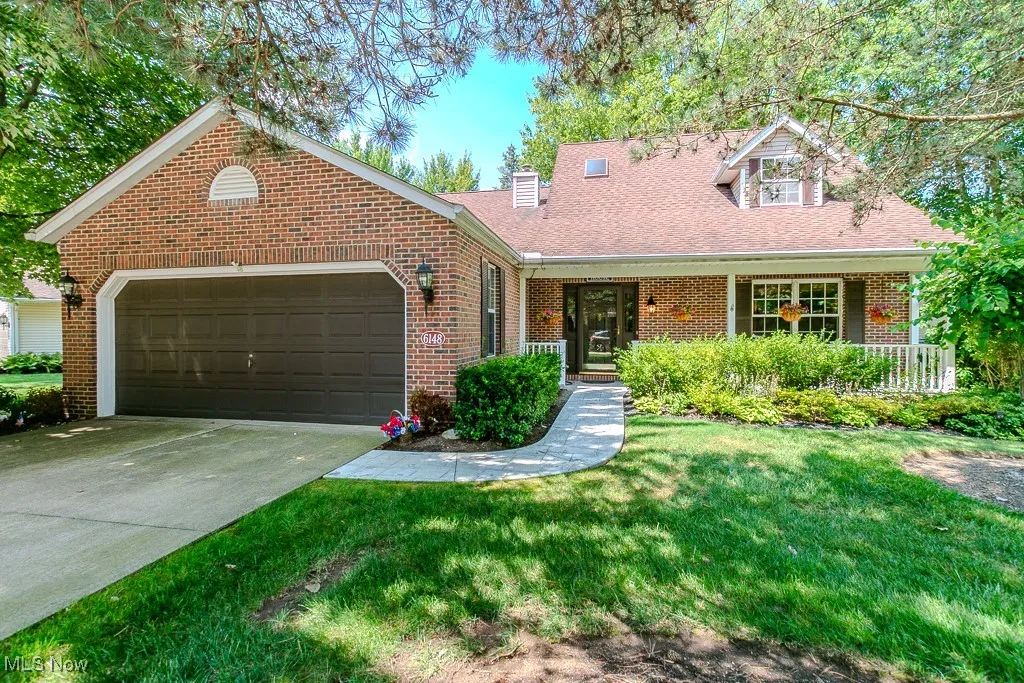 View of front of property featuring a garage, a front lawn, concrete driveway, brick siding, and a porch