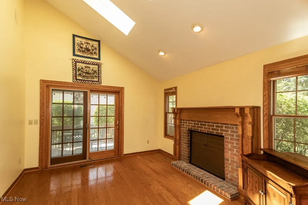 Unfurnished living room featuring a skylight, a fireplace, wood finished floors, plenty of natural light, and recessed lighting