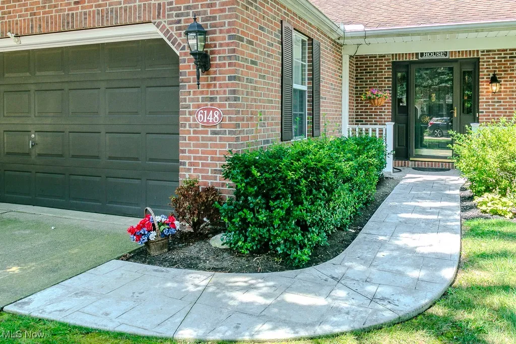 Entrance to property with brick siding, a garage, a shingled roof, and covered porch