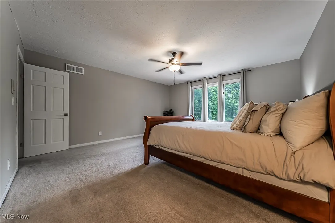 Bedroom #4 views the front of the home and featuring carpet floors, a generous closet and ceiling fan.
