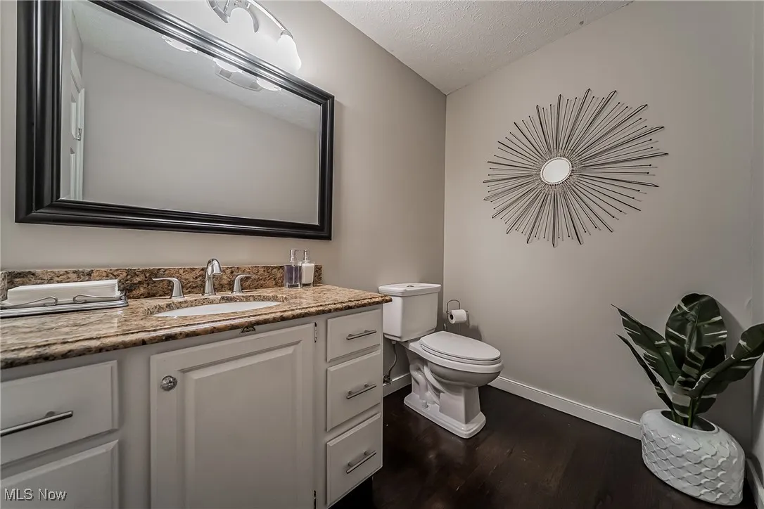 1st floor Half bath featuring wood finished floors, a textured ceiling, and vanity