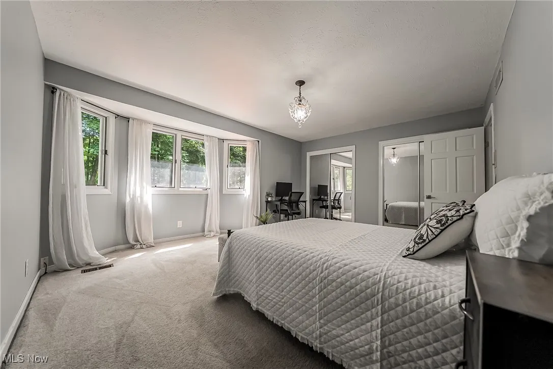 Bedroom #3 featuring carpet flooring, double closets, a chandelier, and and beautiful view to the backyard
