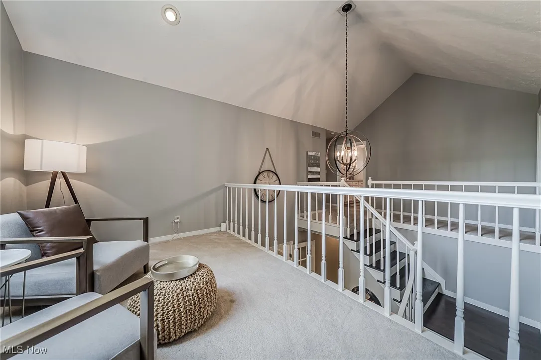 Sitting area accessed on through the primary bedroom suite featuring vaulted ceiling, a chandelier, an and carpet floors