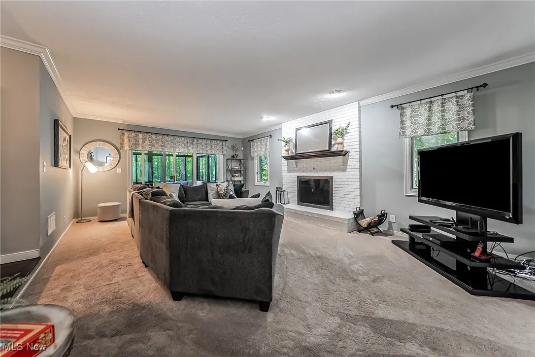 Carpeted living room featuring ornamental molding and a brick fireplace