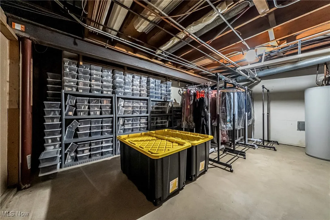 Unfinished storage closet in basement with water heater and furnace
