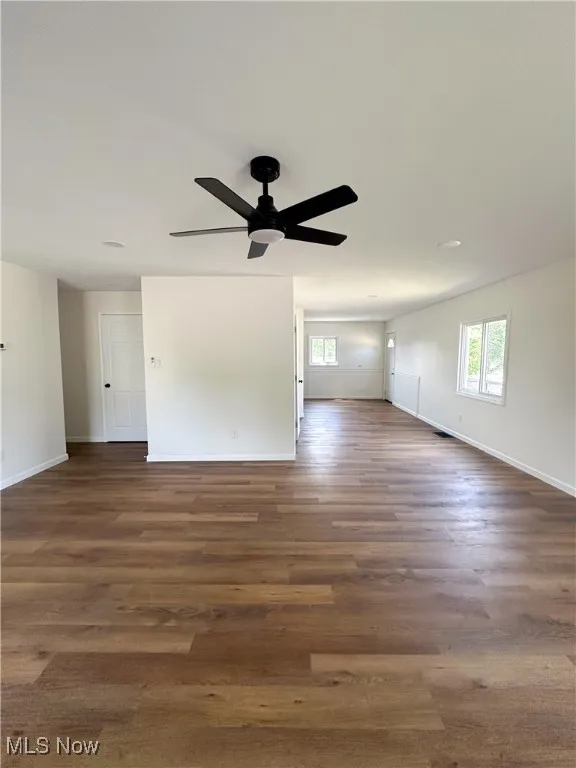 Unfurnished living room with dark wood-style flooring and a ceiling fan