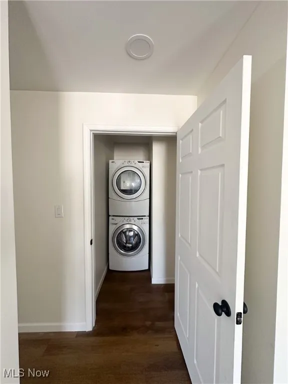 Hall featuring stacked washing machine and dryer and dark wood finished floors
