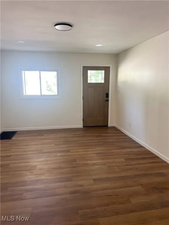 Foyer featuring dark wood finished floors and baseboards