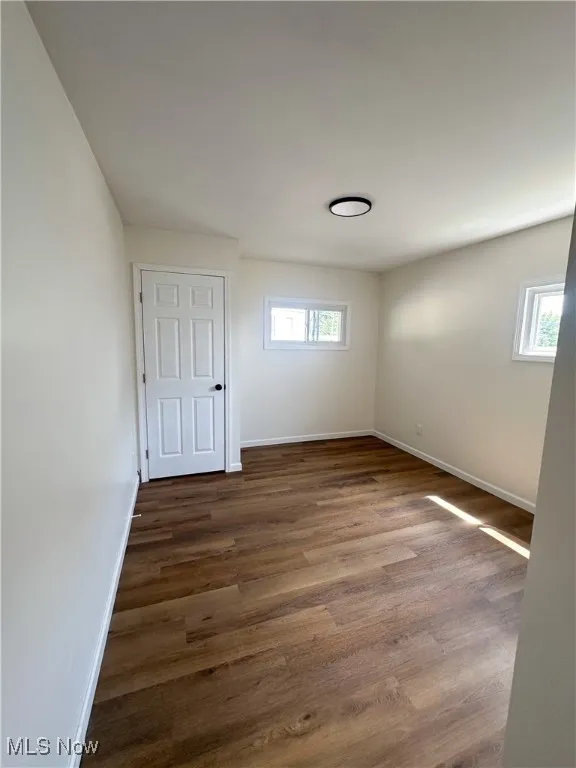 Unfurnished bedroom with dark wood-style floors and baseboards